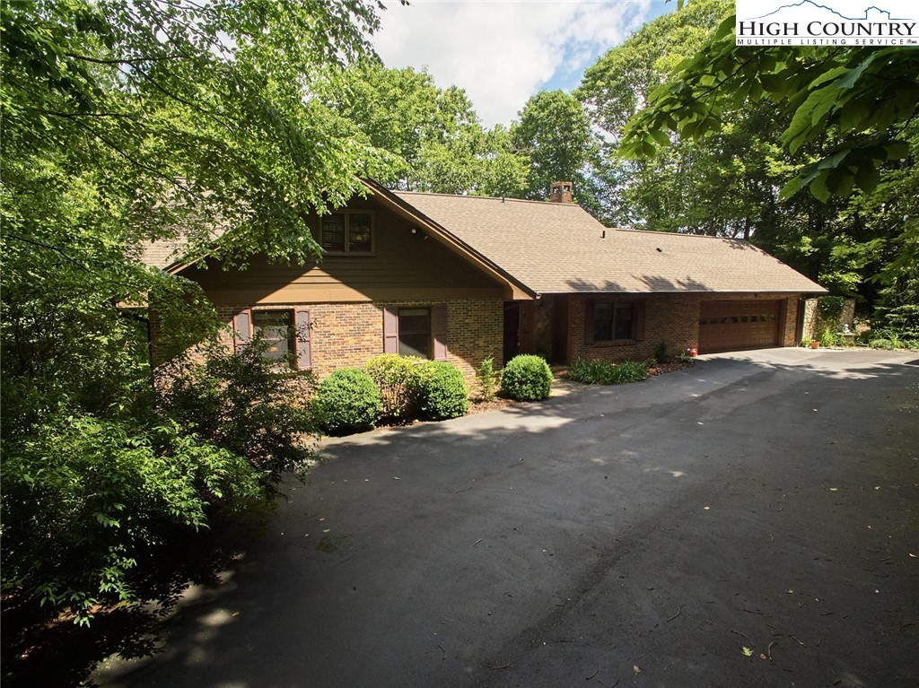 Front of 239 Eagle Drive: stained wood, a broad shingled gable, and the drive under the trees.